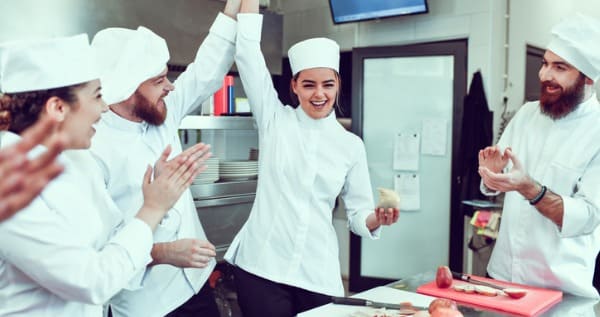 aluna do curso de gastronomia sendo parabenizada por professor entre os alunos
